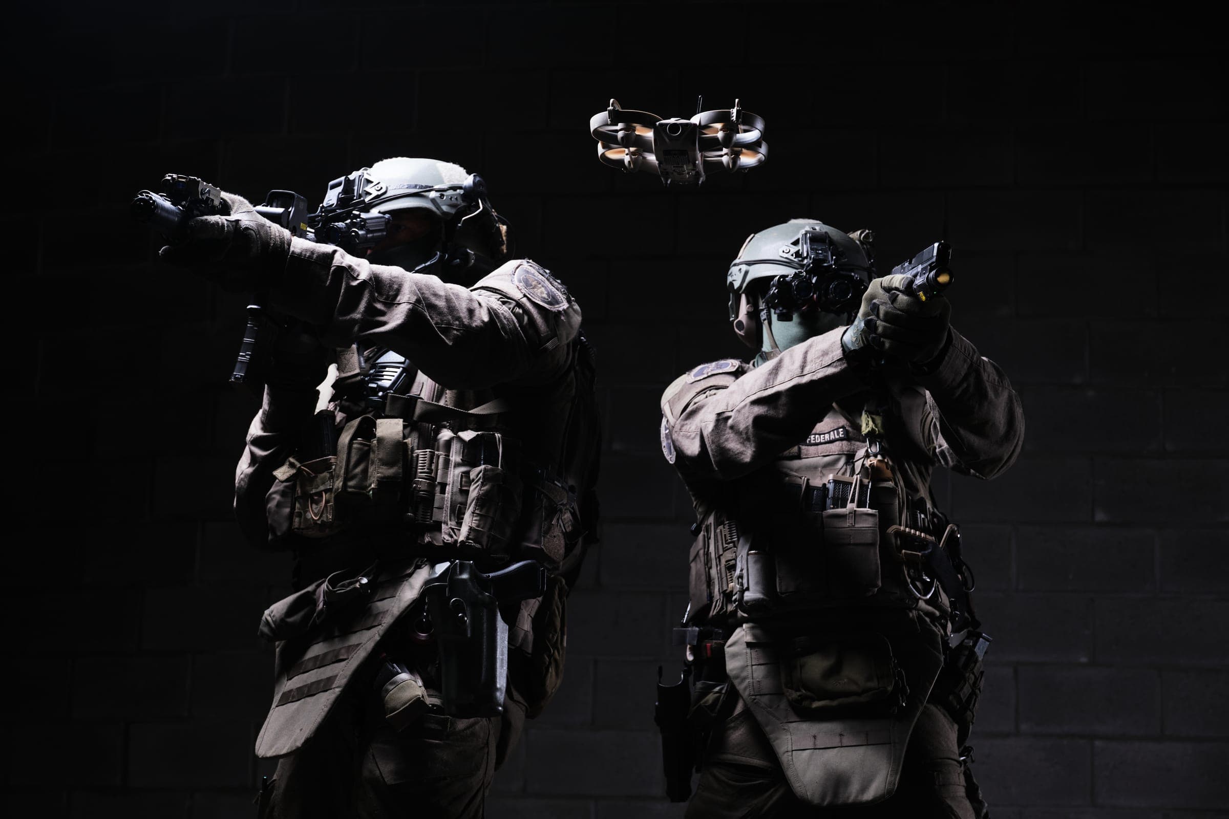 Twee agenten van de federale politie met helm, nachtzicht, headset, plate carrier, pistool met wapenlamp, holster en een drone