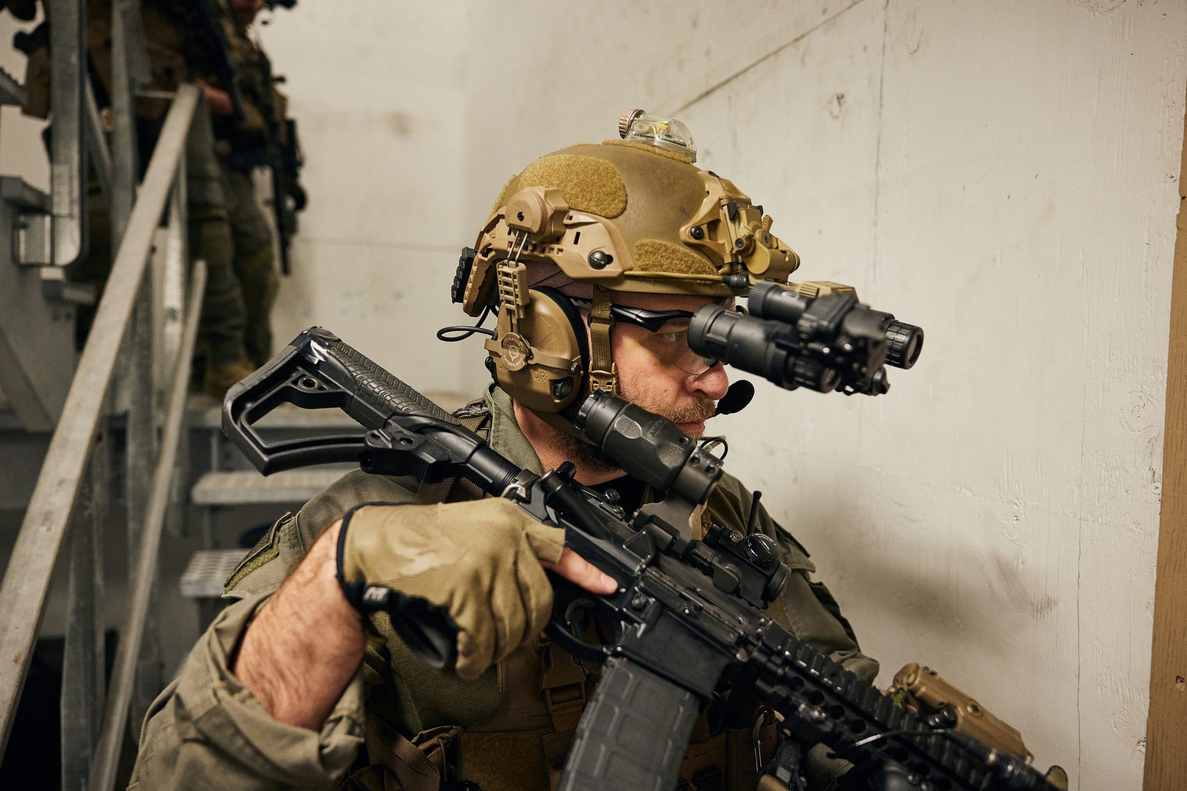 Operator met een helmsysteem (helm, nachtzicht, headset, veiligheidsbril) en een wapensysteem (karabijn, red dot met vergroter, IR-laser)